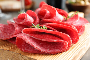 Slices of delicious sausage with thyme served on table, closeup