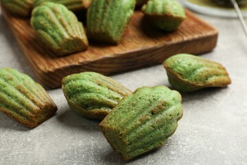 Tasty matcha madeleine cakes on light grey table, closeup