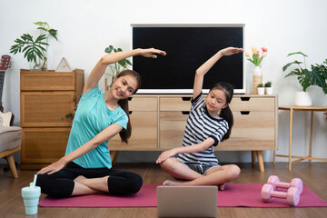 Wellness yoga practice with mother and daughter stretching together