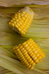 A sliced corn and corn husk leaves on the wooden cutting board.