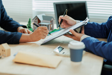 A real estate agent explains interest rates and home purchase contract details to a client, helping...