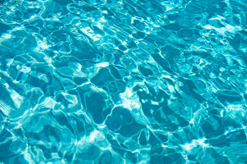 Blue pool water background. Blurred transparent clear calm water surface texture. Water waves in sunlight with copy space.