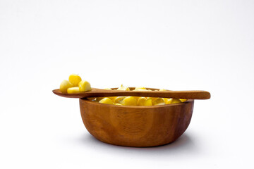 A wooden bowl with corn kernels, isolated on white background.