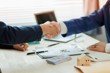 A real estate agent and client shake hands, marking a successful agreement in the home buying process.