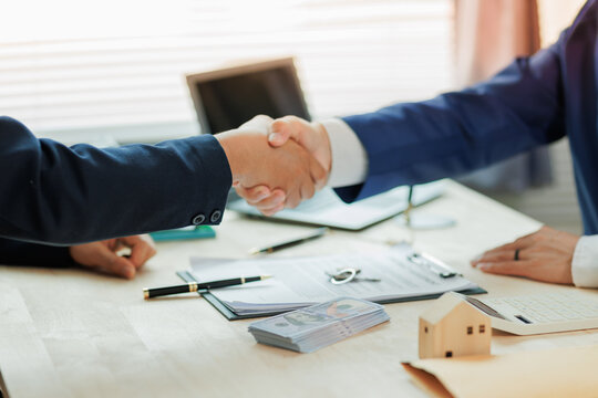 A real estate agent and client shake hands, marking a successful agreement in the home buying process.