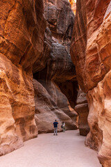 Tourists provide scale to the massive narrow gorge of the Siq entering Petra in Jordan