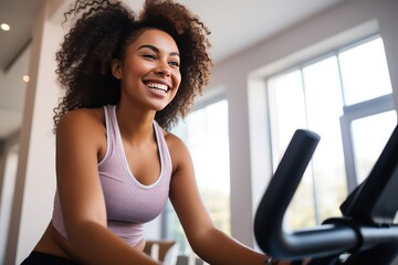 Young African American woman during workout on a smart exercise bike at home. A scientific approach to training for maximum performance.