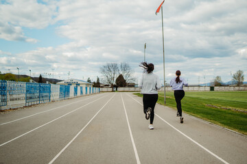 Two female friends running or jogging on stadium doing sport activities