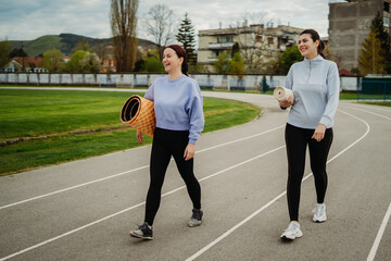 Two female friends stretching on stadium doing sport activities