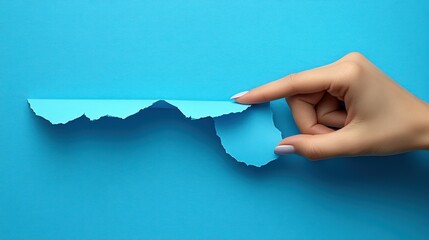 Hand tearing a piece of light blue paper