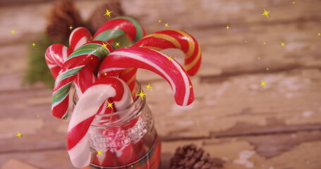 Naklejka premium Image of yellow stars over christmas candy canes