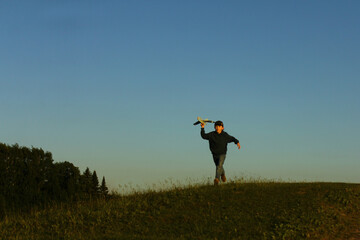 A little boy is playing outside with a toy airplane that he made himself. childhood