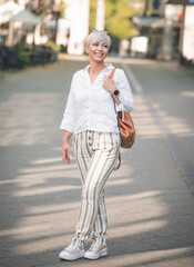 Full body of smiling beautiful woman. Cheerful woman standing and posing on street in the city. Outdoors - outside