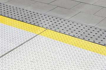 Modern pedestrian surface detail. Yellow tactile strip on sidewalk. Anti-slip textured plates for...