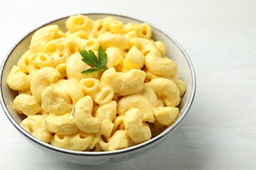 Delicious pasta with cheese sauce in bowl on light table, closeup