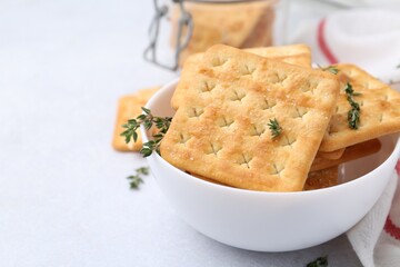 Tasty salty crackers and thyme on white table, closeup