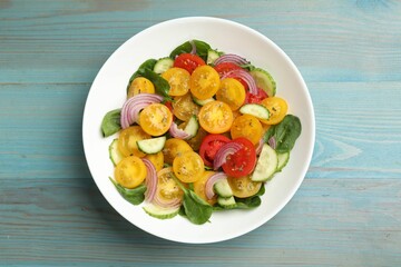 Fresh salad with yellow tomatoes on light blue wooden table, top view