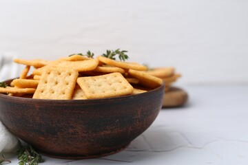 Tasty salty crackers and thyme on white textured table, closeup. Space for text