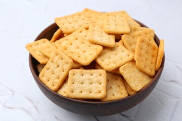 Tasty salty crackers on white textured table, closeup