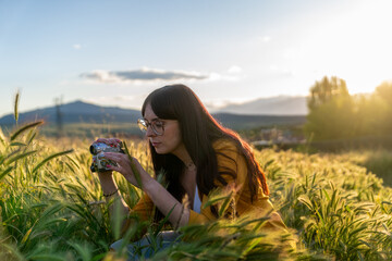 Filmmaker recording with vintage camcorder in a wheat field at sunset