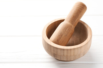 Mortar and pestle on white wooden table, closeup. Space for text