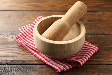 Mortar, pestle and cloth on wooden table, closeup