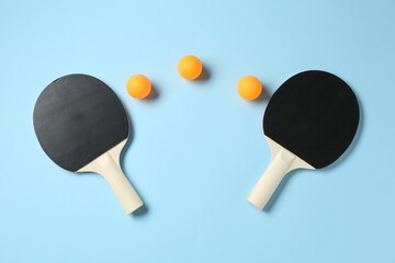 Ping pong rackets and balls on light blue background, flat lay