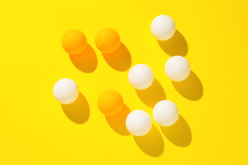 Ping pong balls on yellow background, flat lay