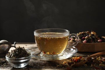 Refreshing herbal tea and dry leaves on wooden table, closeup. Space for text