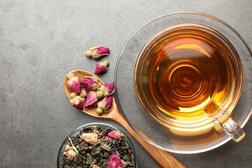 Aromatic herbal tea, dry leaves and flowers on grey table, flat lay. Space for text