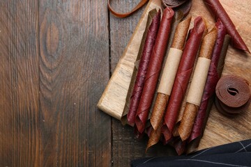 Tasty fruit leather rolls on wooden table, flat lay. Space for text