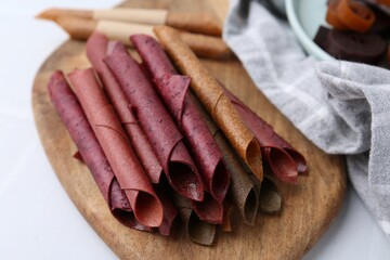 Tasty fruit leather rolls on white table, closeup