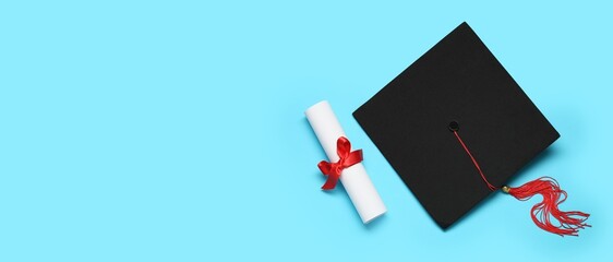 Mortar board and diploma on light blue background with space for text