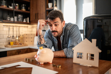 Man saving money for new house, planning domestic budget with piggy bank