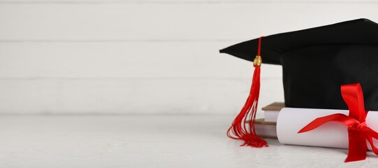 Mortar board, stack of books and diploma on white wooden background with space for text, closeup