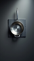 A single cast iron skillet hanging on a wall rack against a dark gray background.