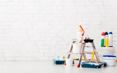 Wall at renovation with ladder and paint buckets in empty room, copy space