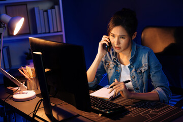 Young beautiful Asian creative woman calling on phone desk to customer or coworker explaining...