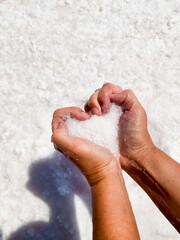 Hands holding salt in heart shape on white background