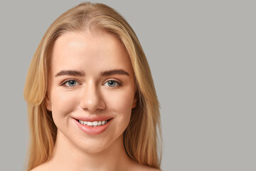 Naklejka premium Smiling young woman with beautiful lips on grey background