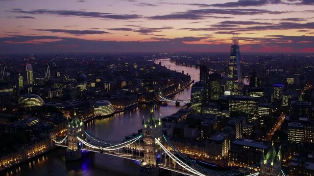 Aerial video shot at sunset captures a sprawling cityscape with a river, under a dramatic sky, blending urban and natural beauty in a panoramic view.