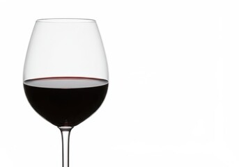 A glass of red wine sits against a plain white background in a studio setting