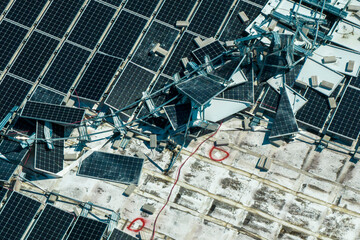 Destroyed by hurricane winds broken down photovoltaic solar panels mounted on industrial building...