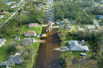 Flooded Florida road with evacuating cars and surrounded with water houses in suburban residential...