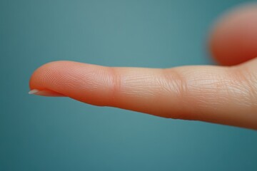 Close up image of an extended human finger against a blue background