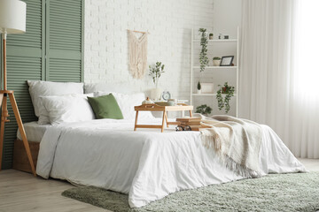 Interior of bedroom with breakfast and books on bed