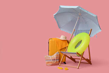 Deck chair, beach umbrella, suitcase, hat, bag, flip-flops and inflatable ring on pink background