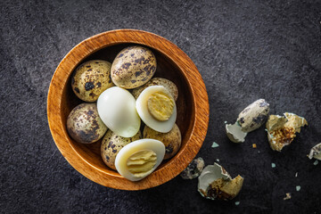 Boiled quail eggs in bowl on black table. Top view.