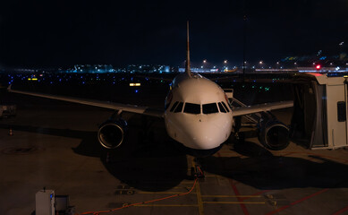 Front landing gear and cockpit of airplane on airport runway at night. Aerospace industry.