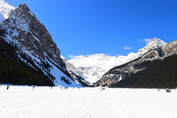 Lake Louise, Alberta, Canada - Apr 13, 2025: Tourists walking on the frozen Lake Louise. Beautiful Lake Louise in spring. The lake is frozen with unreal, scenic nature views in popular tourism area.